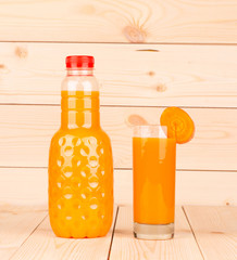 Close up of carrot juice in glass and bottle.