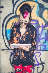 Fototapeta premium Smiling young woman using digital tablet in front of graffiti wall