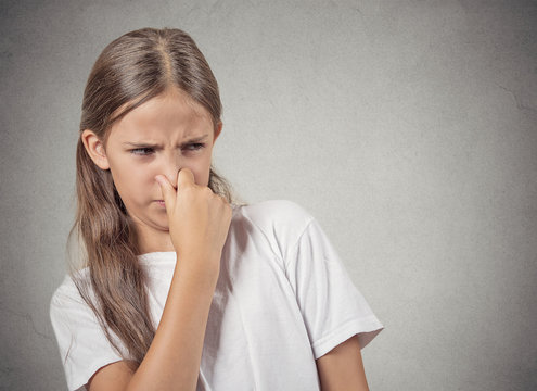 teenager girl pinches nose, something stinks bad smell 