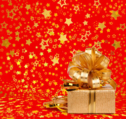 Gift box in gold wrapping paper on a beautiful red abstract back