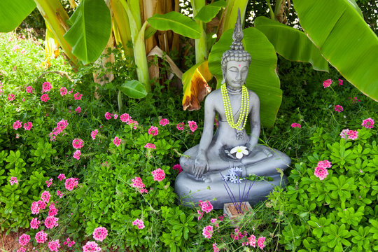 Buddha - Buddhastatue im grünen Garten und Räucherstäbchen