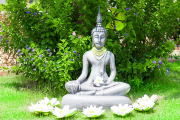 Tempel - Buddhastatue im grünen Garten mit Blüten