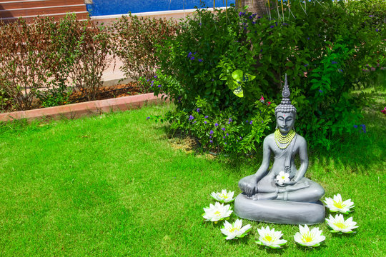 Tempel - Buddhastatue im grünen Garten mit Blüten