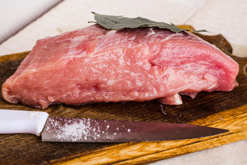 raw meat on a cutting board with spices, knife