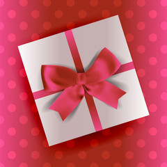A white gift with a pink ribbon and a bow