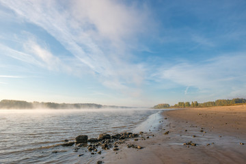 Fototapeta na wymiar Sandy beach misty river early in the morning