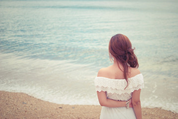 Fototapeta na wymiar young woman in white dress looking the beach