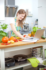 Frau mit laptop in der küche 