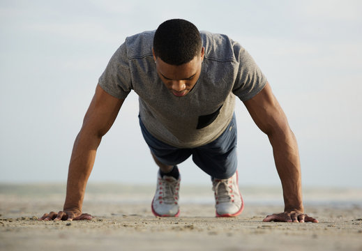 Fit young man doing push ups at the beach