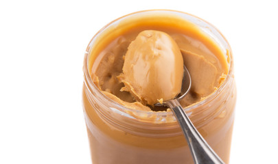 An opened jar of peanut butter with a small spoon