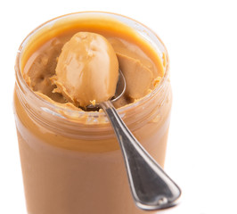 An opened jar of peanut butter with a small spoon