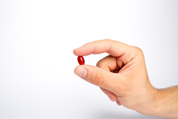 Zwei Finger halten eine rote Tablette