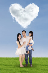 Fototapeta na wymiar Cheerful family under cloud shaped heart