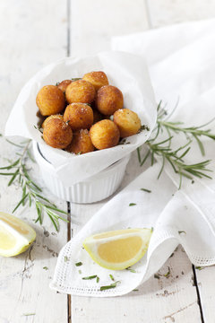 balls of fried potatoes with lemon and rosemary on table