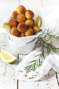 balls of fried potatoes with lemon and rosemary on table