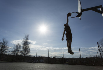 Silhouette basketball player slam dunking outdoors © icsnaps