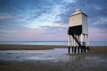 Sunrise landscape of wooden stilt lighthouse on beach in Summer