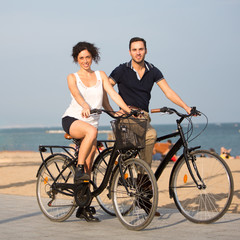 Two persons cycling on a city beach