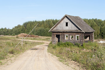 Fototapeta na wymiar Dirt road and abandoned wooden house