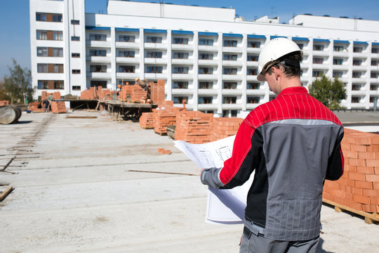 Builder worker with drawing at construction site