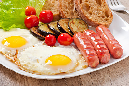 English breakfast - fried eggs, sausages, eggplant and tomatoes