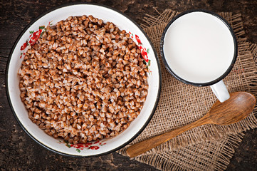 Buckwheat in an old bowl and mug of milk on a rustic style