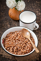 Buckwheat in an old bowl and mug of milk on a rustic style