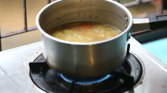 stirred ladle chicken soup in saucepan on gas stove