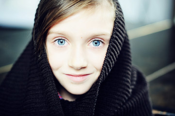 Kid girl in knitted snood on brick wall background