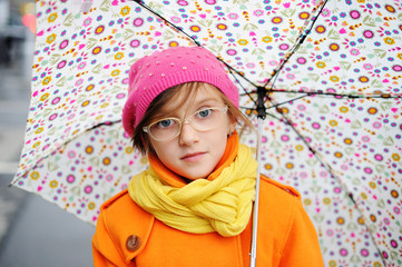 Colorful kid girl with umbrella on city street