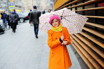 Colorful kid girl with umbrella on city street