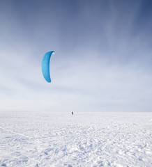 Kiteboarder with blue kite on the snow
