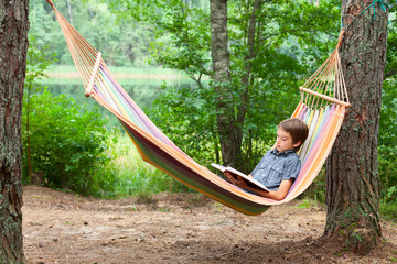 Child reading book in hammock