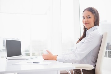 Happy businesswoman having coffee at her desk