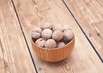 whole walnuts lying on faded wood with additional nuts in wooden