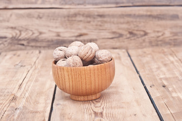 whole walnuts lying on faded wood with additional nuts in wooden
