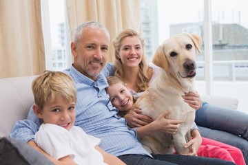 Fototapeta premium Parents and their children on sofa with labrador
