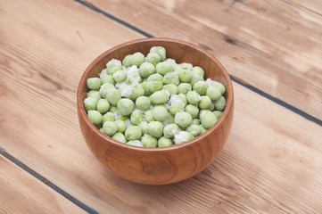 Frozen peas in a wooden  bowl on a wooden table