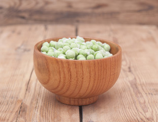 Frozen peas in a wooden  bowl on a wooden table