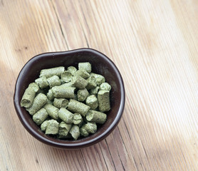 beer ingredients: toppellets of hops on wooden table