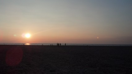 Persone sulla spiaggia al tramonto, l'estate è finita