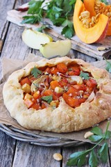 Pumpkin-apple galette with onion and bacon on a wooden table