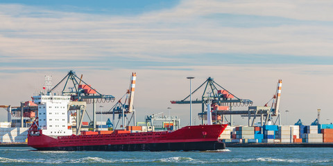 Container ship passing cranes in Rotterdam harbor