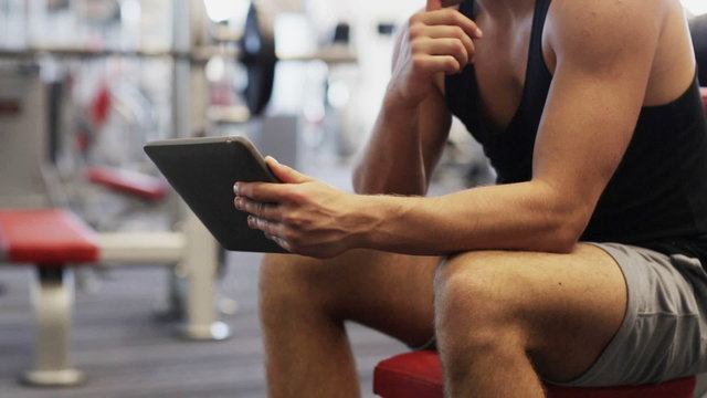 young man with tablet pc computer in gym