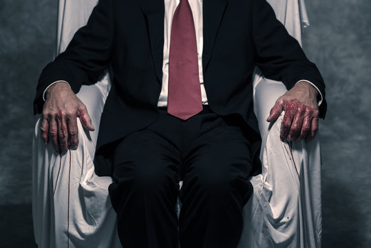 Bloody hand of businessman sitting in white chair.