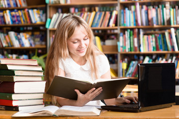 pretty female student typing on notebook in library
