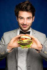 Mann im Anzug mit Burger in der Hand