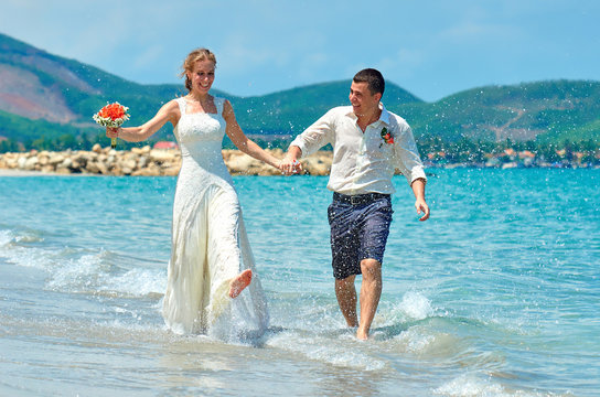Happy Bride and groom running on a beautiful tropical beach