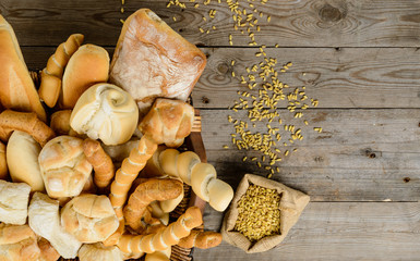 Vari tipi di pane e chicchi su piano di legno 