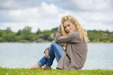 Fototapeta premium Blond woman sitting at lake